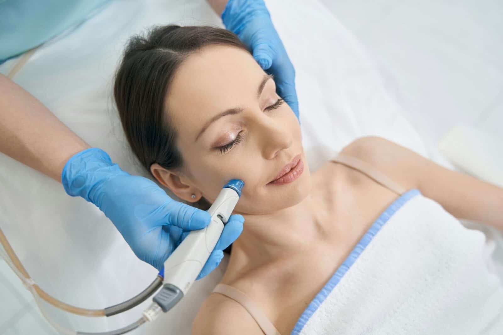 Woman receiving hydrafacial treatment in beauty salon